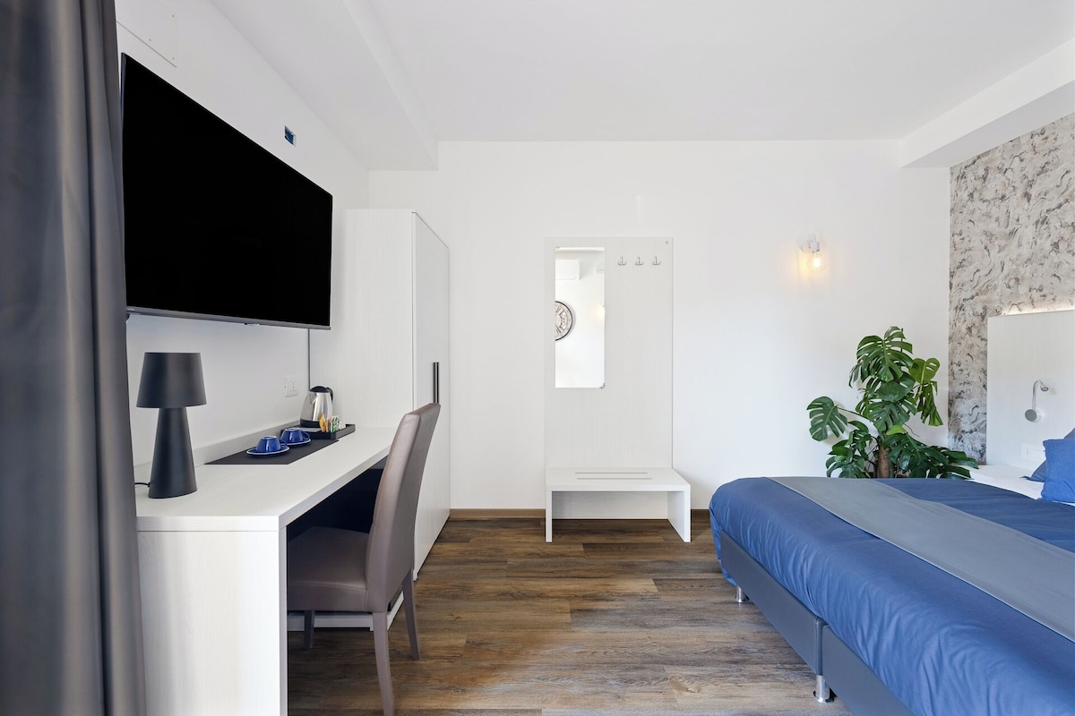 Un dormitorio moderno con cama, escritorio, silla y una planta en maceta.