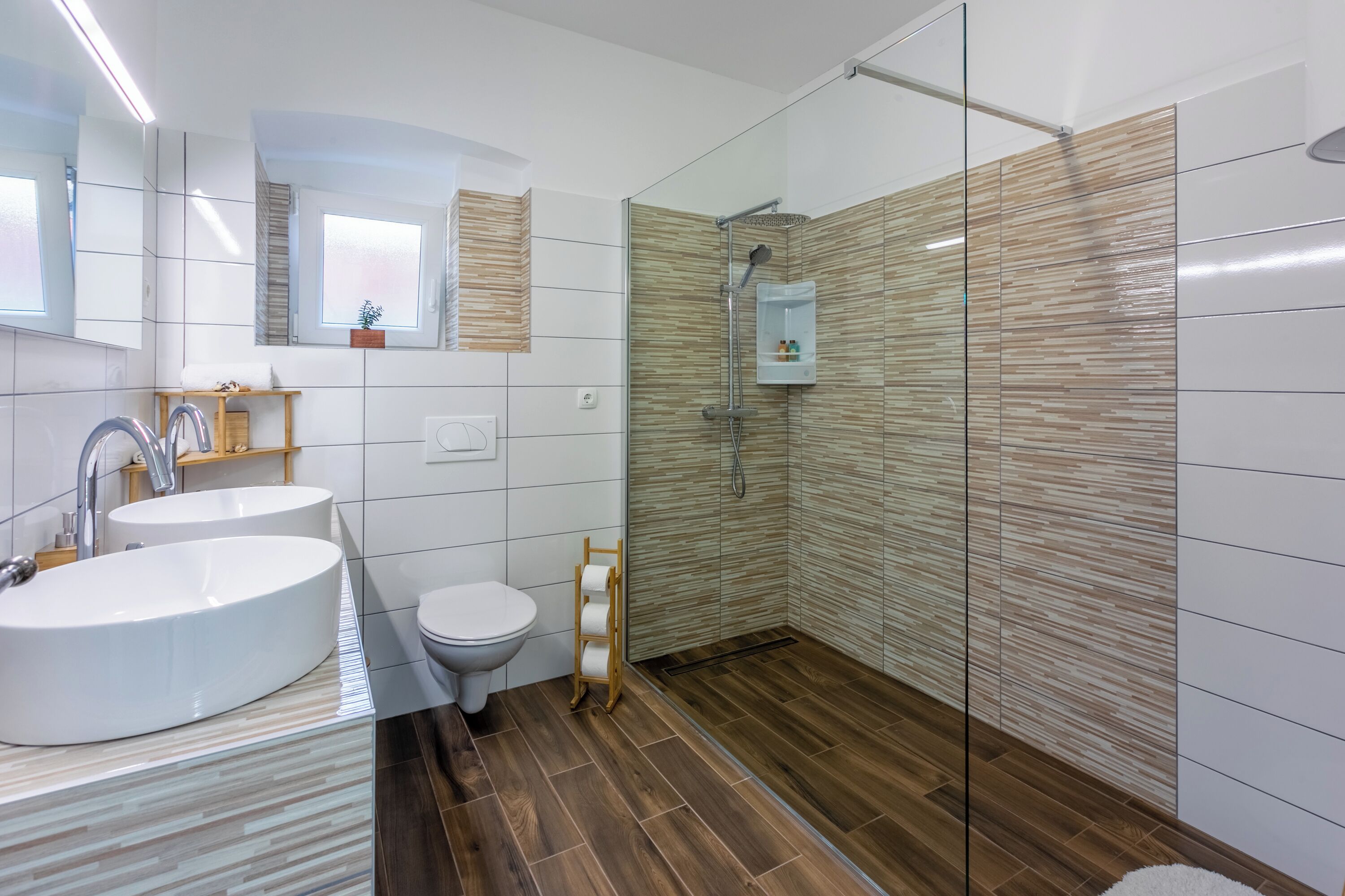 Une salle de bain moderne avec deux lavabos, des toilettes, une douche et un miroir.