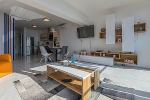 A modern living room with a TV, sofa, coffee table, and kitchen in the background. - Fantastic luxury apartment with private whirlpool (Crikvenica)