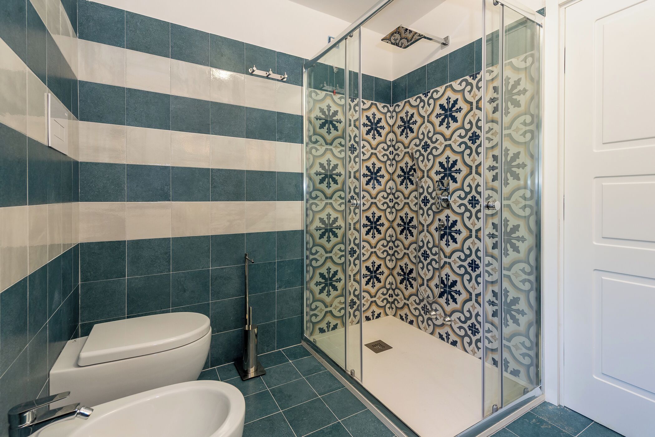 A bathroom with a shower, toilet, and bidet.