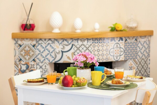 A breakfast table with plates of food, a vase of flowers, and a tiled backsplash. - B&B Fonte Silente (Roccadaspide)