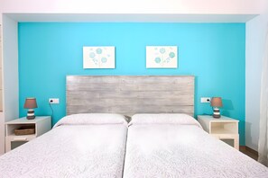 A double bed with a wooden headboard, two bedside tables with lamps, and two wall-mounted floral artwork. - Apartment 'Marcos' with Balcony, Wi-Fi and Air Conditioning (Port de Pollença)