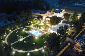 A hotel with a swimming pool, lounge chairs, and a well-lit garden area. - Villa La Personala | Historic Villa with Pool in the Modenese Countryside (Mirandola)