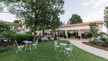 A courtyard with outdoor seating, a building entrance, and a tree.