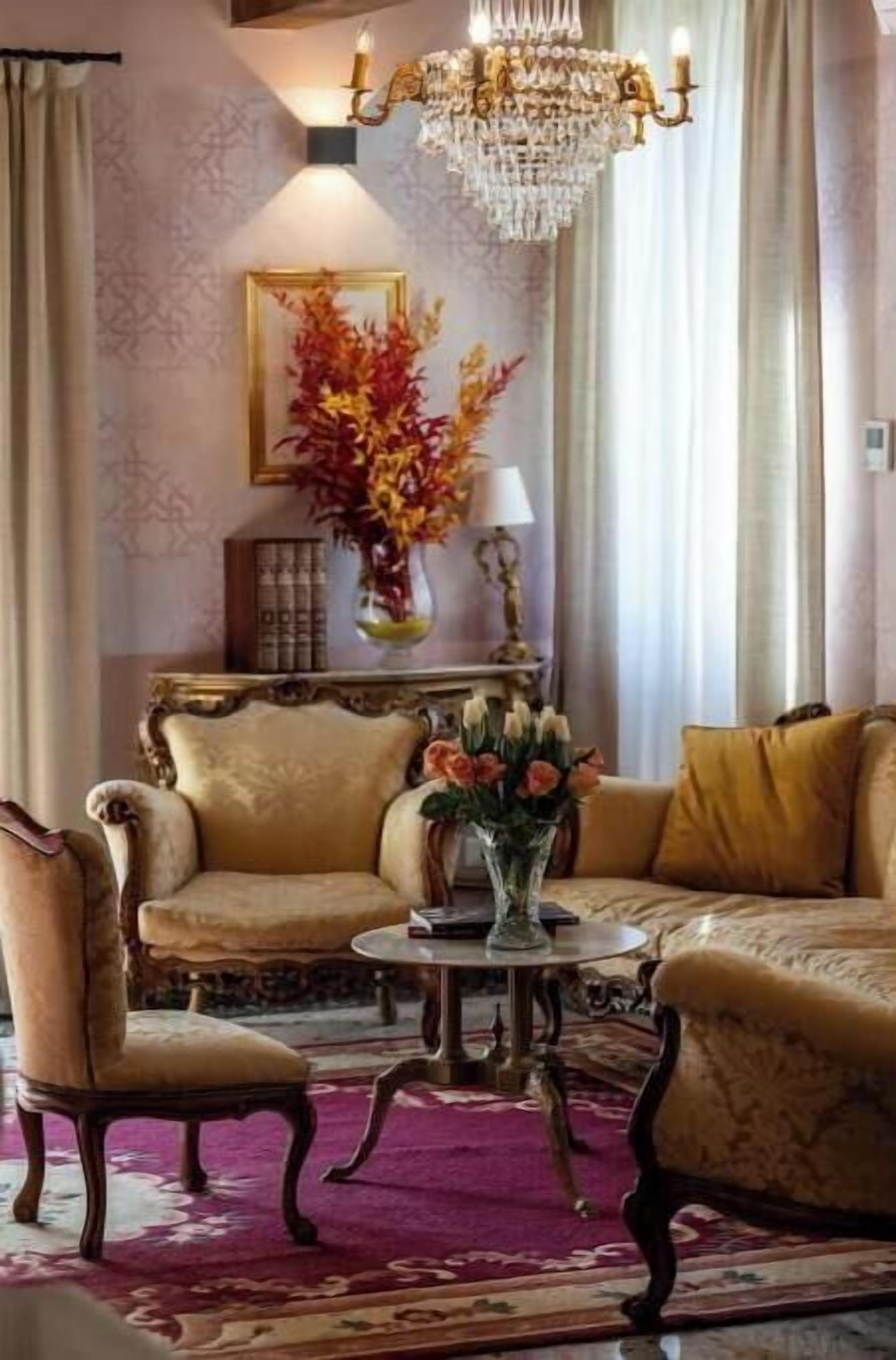 Ein Raum mit einer Chandelier, zwei Sofas, einem kleinen Tisch und einer Zierurne.