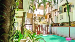 An indoor swimming pool with a waterfall feature, surrounded by potted plants and a multi-level building structure. - Palette Boracay Isle by The White Beach (Boracay Island)