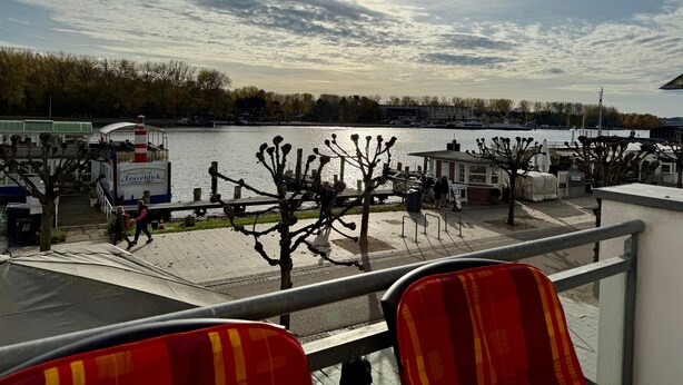 A riverside view with a boat dock, a small building, and trees. - Apartment 'Traveperle 1' with Private Terrace and Wi-Fi (Lübeck)