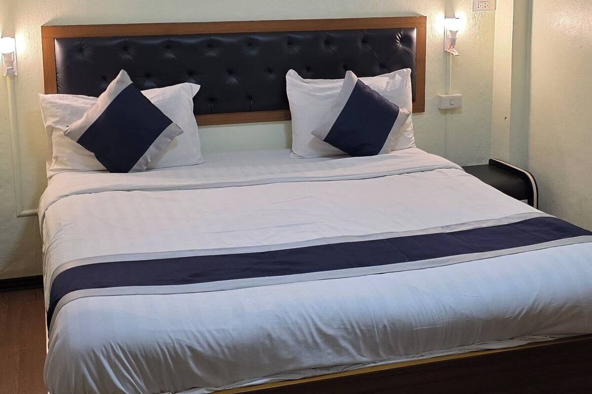 A neatly made bed with a wooden headboard, two bedside lamps, and a welcome mat on the floor.
