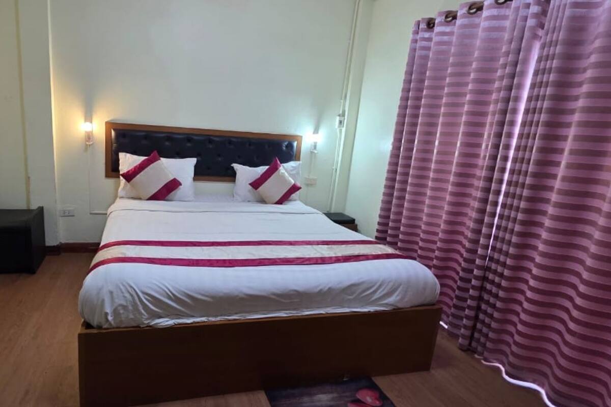 A neatly made bed with a headboard, a bedside table, and a wall-mounted lamp.