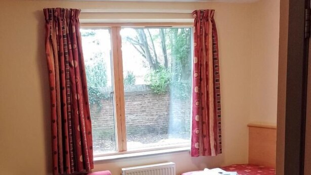 A room with a bed, a chair, a radiator, and a window with curtains. - St John's College (Durham)