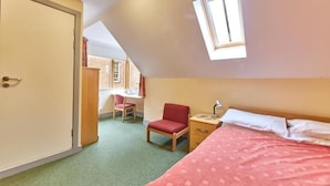 A bedroom with a bed, a desk, a chair, and a window. - St John's College (Durham)