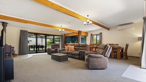 A spacious living room with a fireplace, a dining area, and a large sliding glass door leading to an outdoor patio. - Air on Aldersey (McLaren Vale)