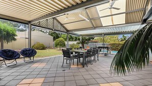 A covered patio with a table and chairs, a ceiling fan, and a view of a swimming pool. - Air on Aldersey (McLaren Vale)