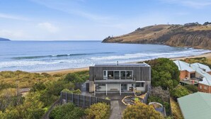 A modern two-story house with a balcony overlooking a beach and ocean. - Beachfront Escape in Clifton (Clifton Beach)