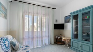 Een kamer met een bank, een kast, een televisie en een tafel met een bloemrijk tafelkleed.