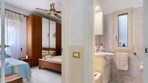 Een slaapkamer met een bed, nachtkastje en een kledingkast.