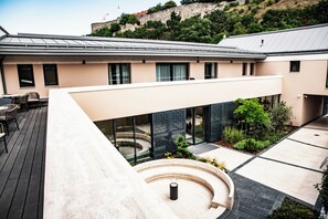 Ein modernes Gebäude mit flachem Dach, großen Fenstern und einem Innenhof mit Außenbestuhlung.