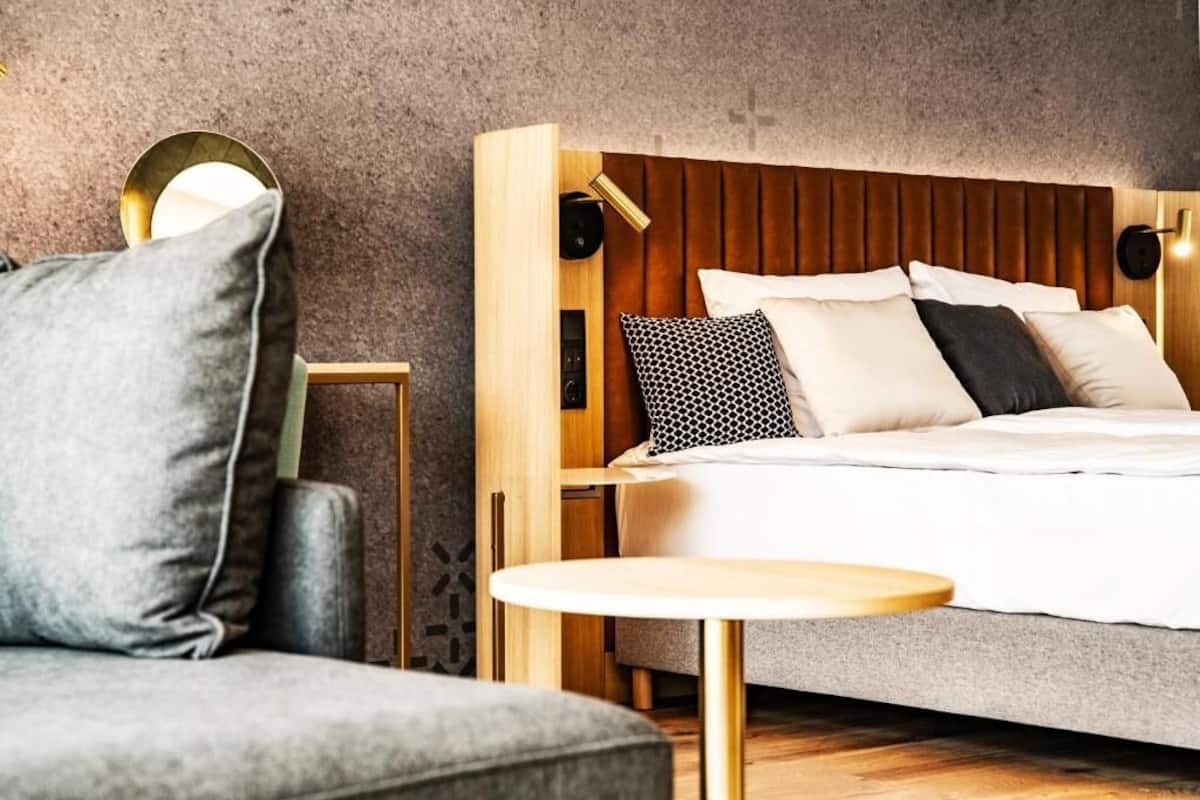Un dormitorio moderno con cabecera de madera, una mesa redonda y un sofá gris.