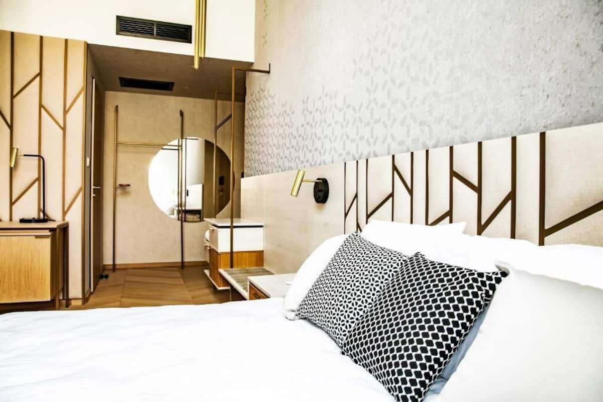 Una habitación de hotel moderna con cama, mesita de noche y espejo.