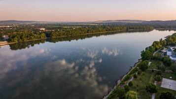 A river with a reflection, surrounded by greenery and buildings.