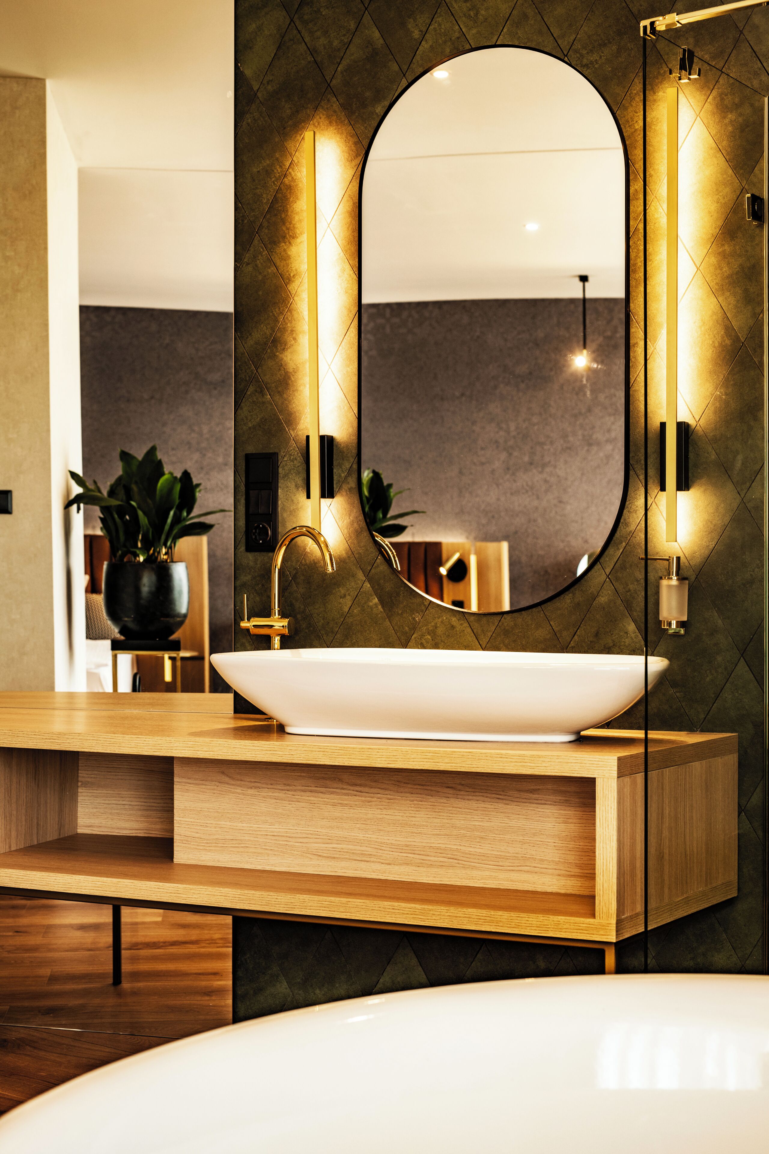 A modern bathroom with a large oval mirror, a vessel sink, and a wooden vanity.