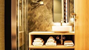 Ein modernes Badezimmer mit Glasdusche, einem großen Spiegel, einem Waschbecken und einem Handtuchhalter.