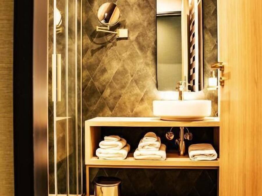 Ein modernes Badezimmer mit Glasdusche, einem großen Spiegel, einem Waschbecken und einem Handtuchhalter.