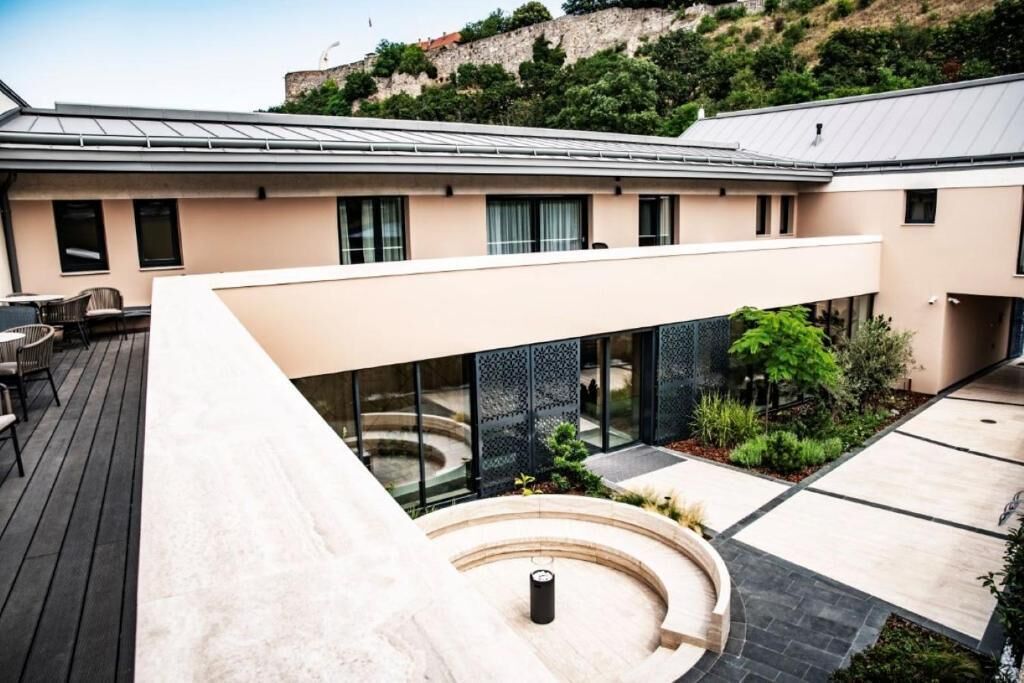 Un edificio moderno con techo plano, ventanas amplias y un patio con zona de estar circular.