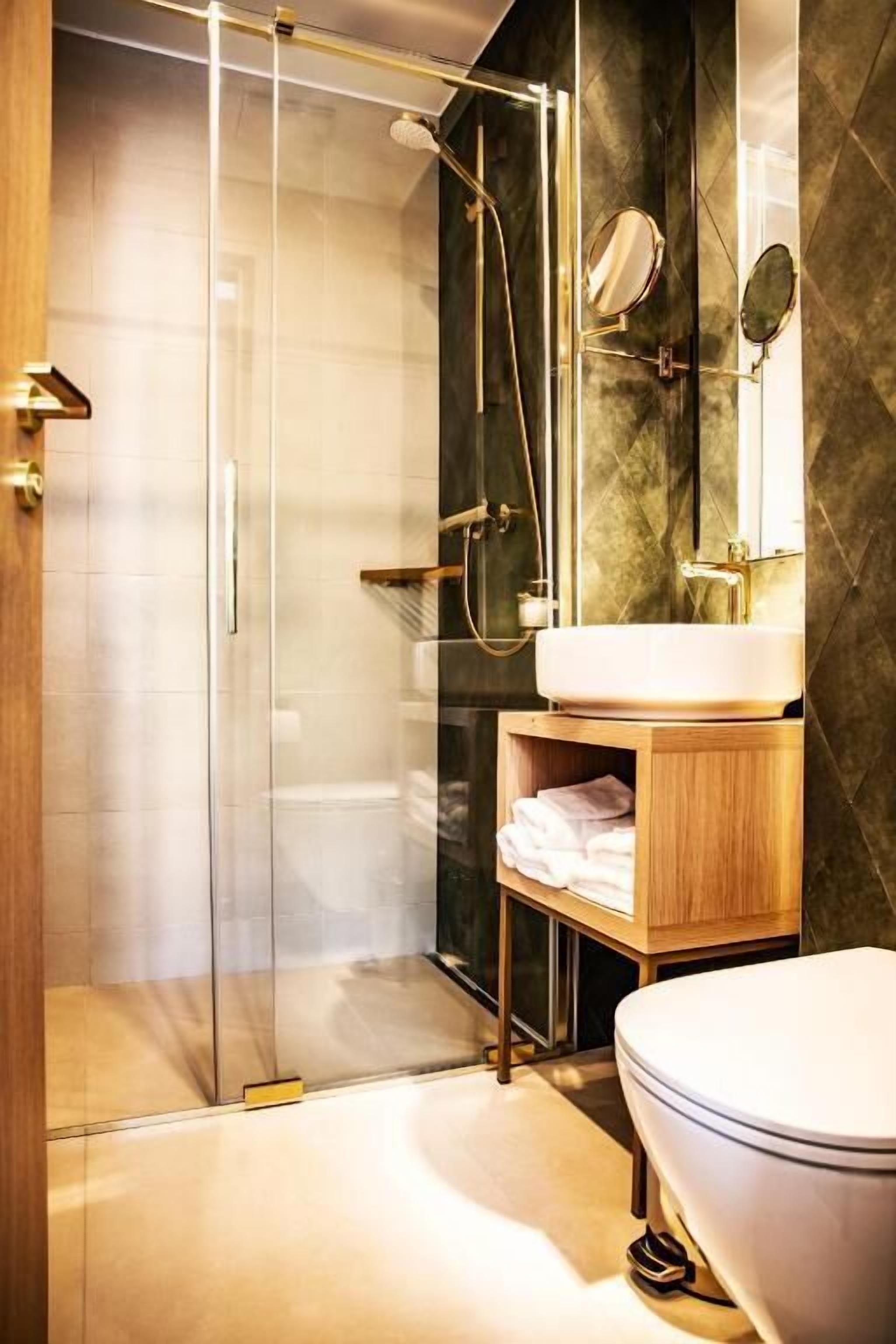 A modern bathroom with a glass-enclosed shower, a wooden vanity, and a white toilet.