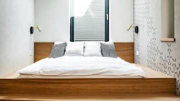 A bedroom with a bed, wooden beams, a skylight, and a patterned wall.