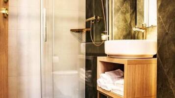 A modern bathroom with a glass shower enclosure, a wooden vanity with a mirror, and a white toilet.