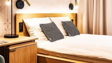 Een hotelkamer met een houten bed, twee bedlampen, een nachtkastje, een bureau en een stoel.