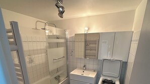 A compact bathroom with a bathtub, a shower, a sink, and a toilet. - Charming fully furnished T2 (Chavanay)