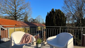 A deck with two white chairs, a small round table, and a potted plant. - Apartment in Garding with gym (Garding)