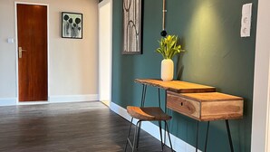 A hallway with a wooden desk, a vase with flowers, a hanging light fixture, and artwork on the wall. - Apartment in Garding with gym (Garding)