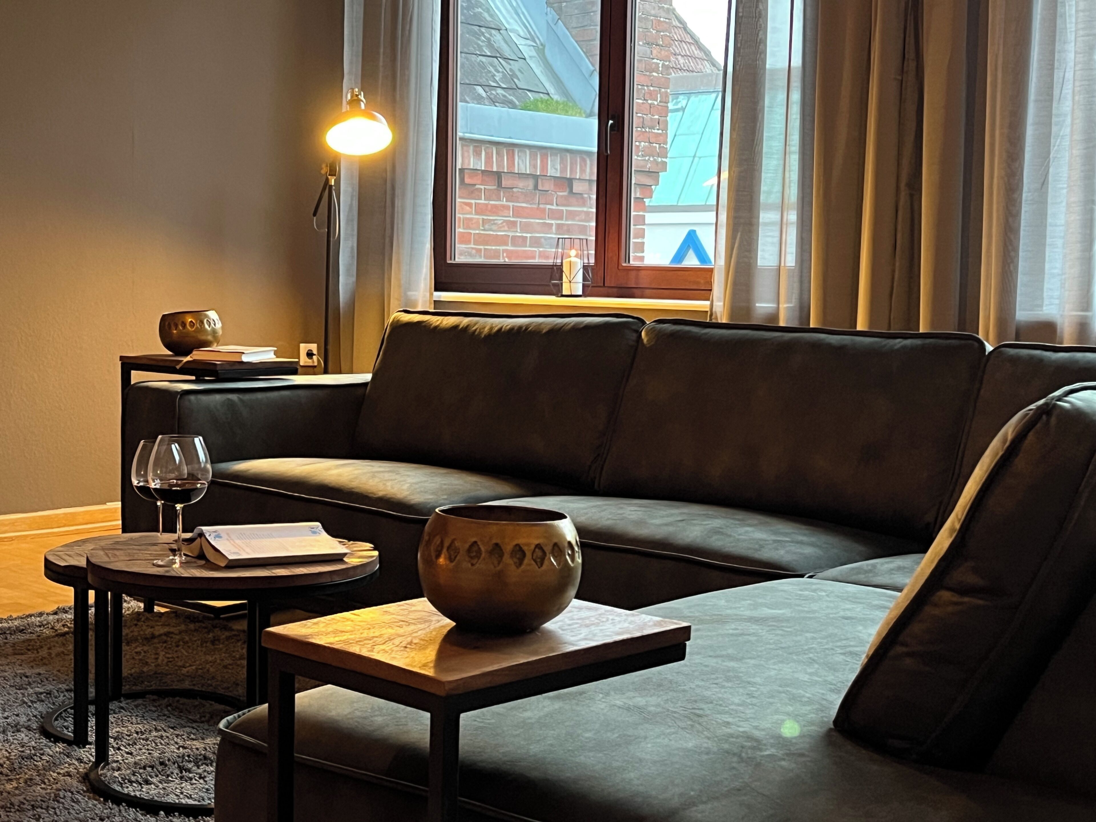 Ein stilvolles Wohnzimmer mit einer Couch, einem kleinen Tisch, einer Schale und einer Lampe.