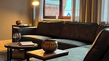 Ein stilvolles Wohnzimmer mit einer Couch, einem kleinen Tisch, einer Schale und einer Lampe.