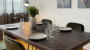 Een eetruimte met een tafel voor vier personen, stoelen, een plant en kunst aan de muur.