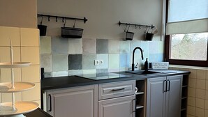 Een moderne keuken met grijze kastjes, een zwart aanrecht en een raam met uitzicht.