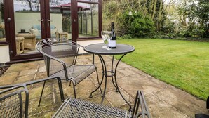A patio with metal chairs and a table, a bottle of wine, and a glass on the table. - Millers Retreat (Chesterfield)