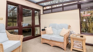 A sunroom with a glass ceiling, wicker furniture, and a view of the outdoors. - Millers Retreat (Chesterfield)
