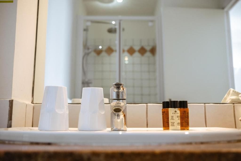 Een wastafel met toiletartikelen en een douche op de achtergrond.