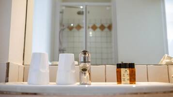 Een wastafel met toiletartikelen en een douche op de achtergrond.