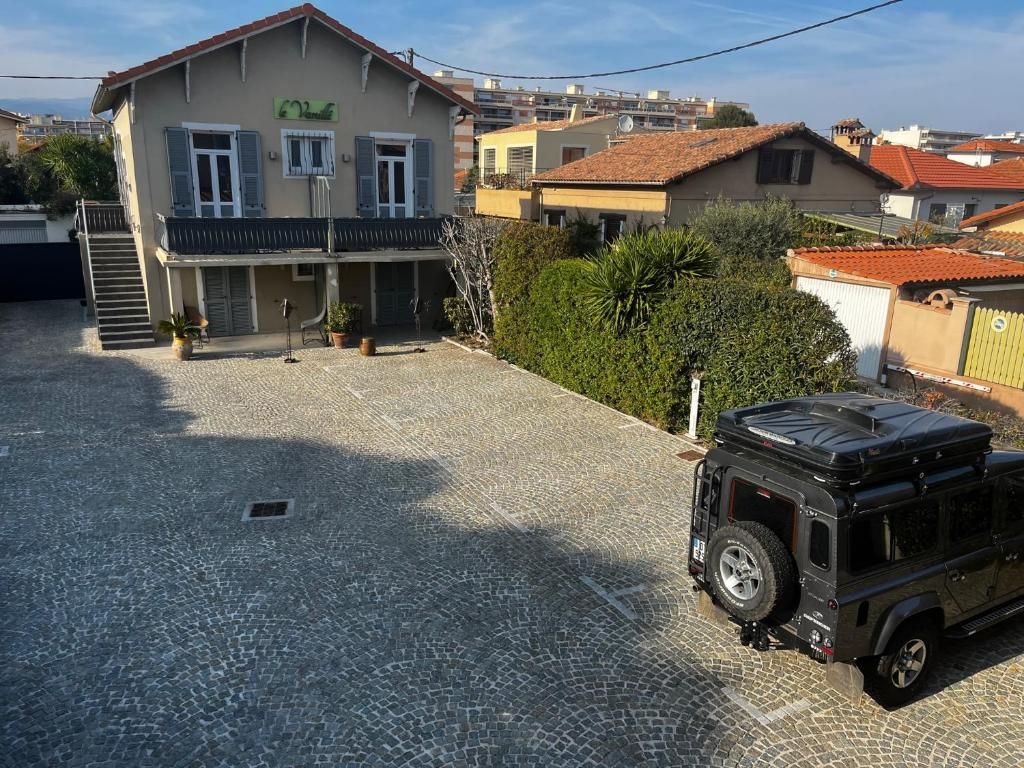 Un bâtiment doté d’un balcon, un véhicule garé devant, et une allée pavée.