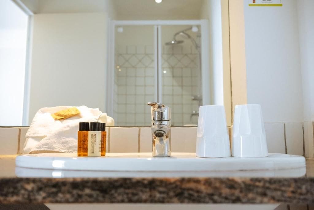 Un mueble de baño con espejo, grifo y artículos de aseo.