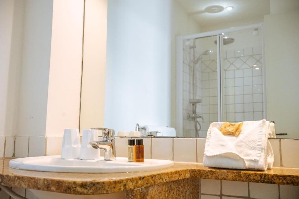 A bathroom with a sink, mirror, and shower.