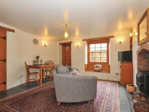 A cozy room with a fireplace, a dining area, and a large window. - Jolly Crabber (St Austell)
