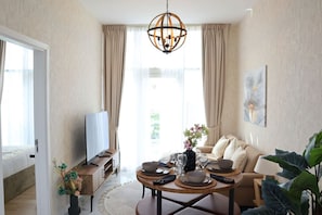 Une chambre d’hôtel moderne dotée d’un coin repas, d’un canapé, d’une télévision et d’une grande fenêtre.