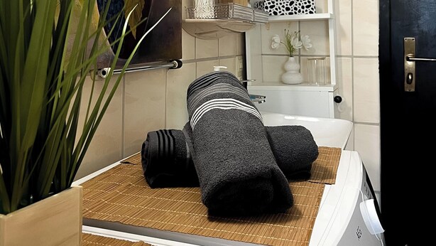 Quarto com mesa de massagem, quadro, prateleira com objetos e porta.