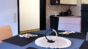 Uma cozinha moderna com armários de madeira, bancada preta e um espaço de refeições com mesa posta para dois.